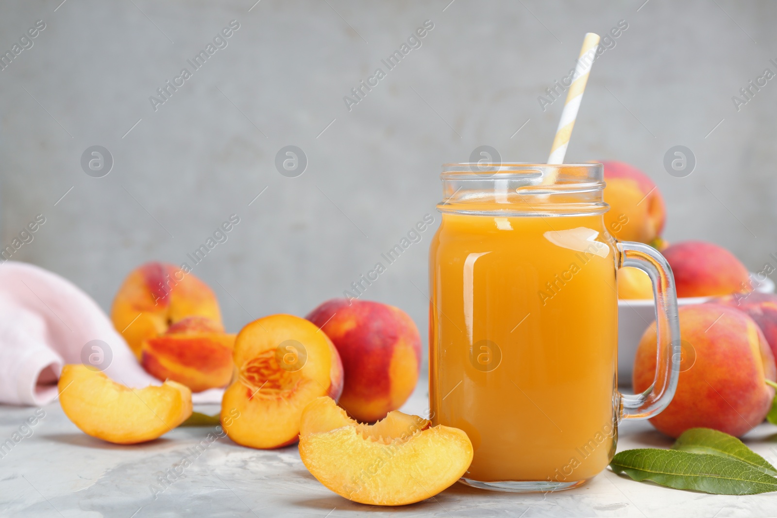 Photo of Natural peach juice and fresh fruits on grey table