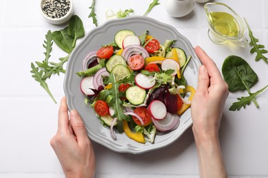 Balanced diet and vegetarian foods. Woman with plate of different delicious products at white table, top view