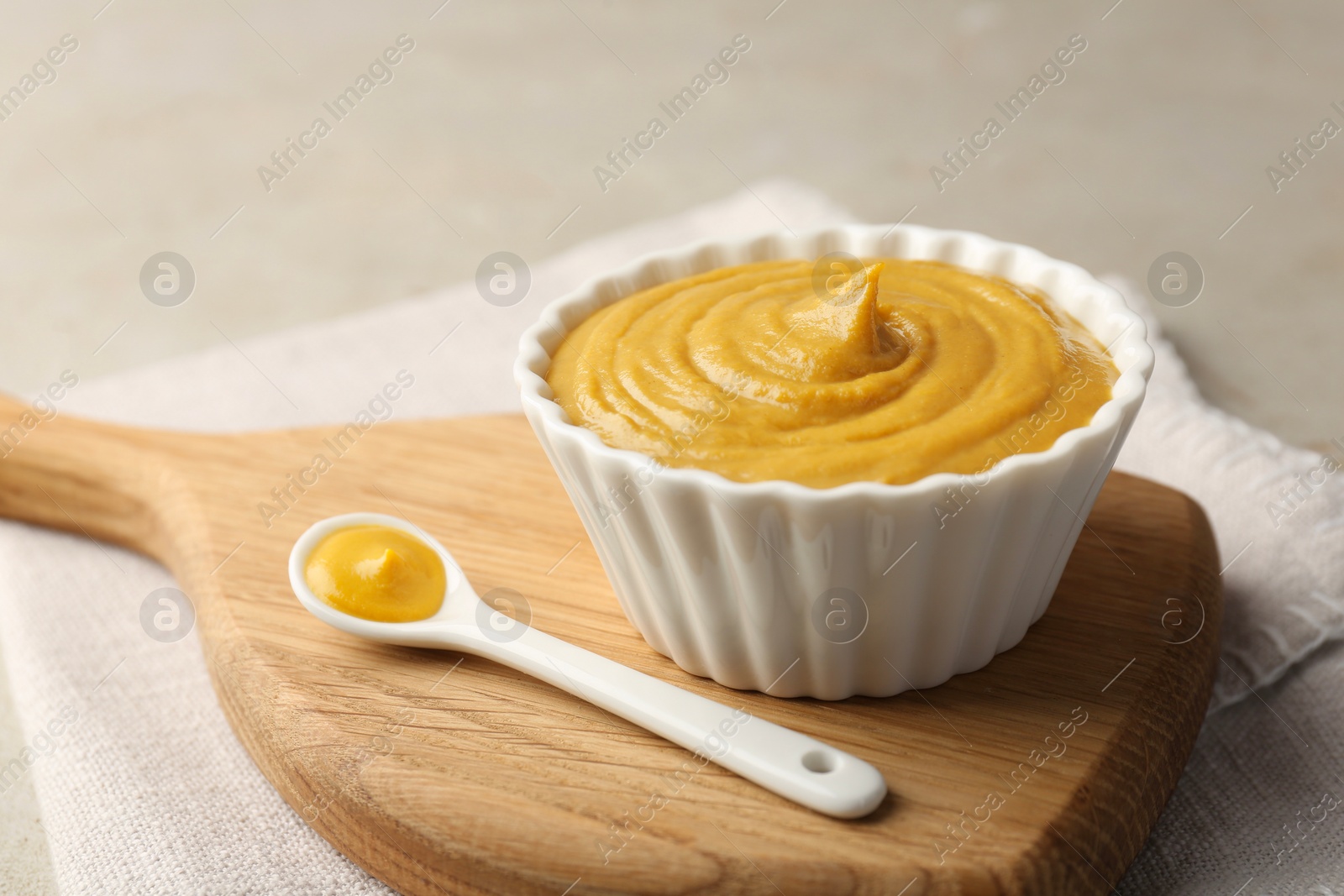 Photo of Bowl and spoon with tasty mustard sauce on light table