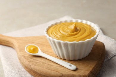 Bowl and spoon with tasty mustard sauce on light table