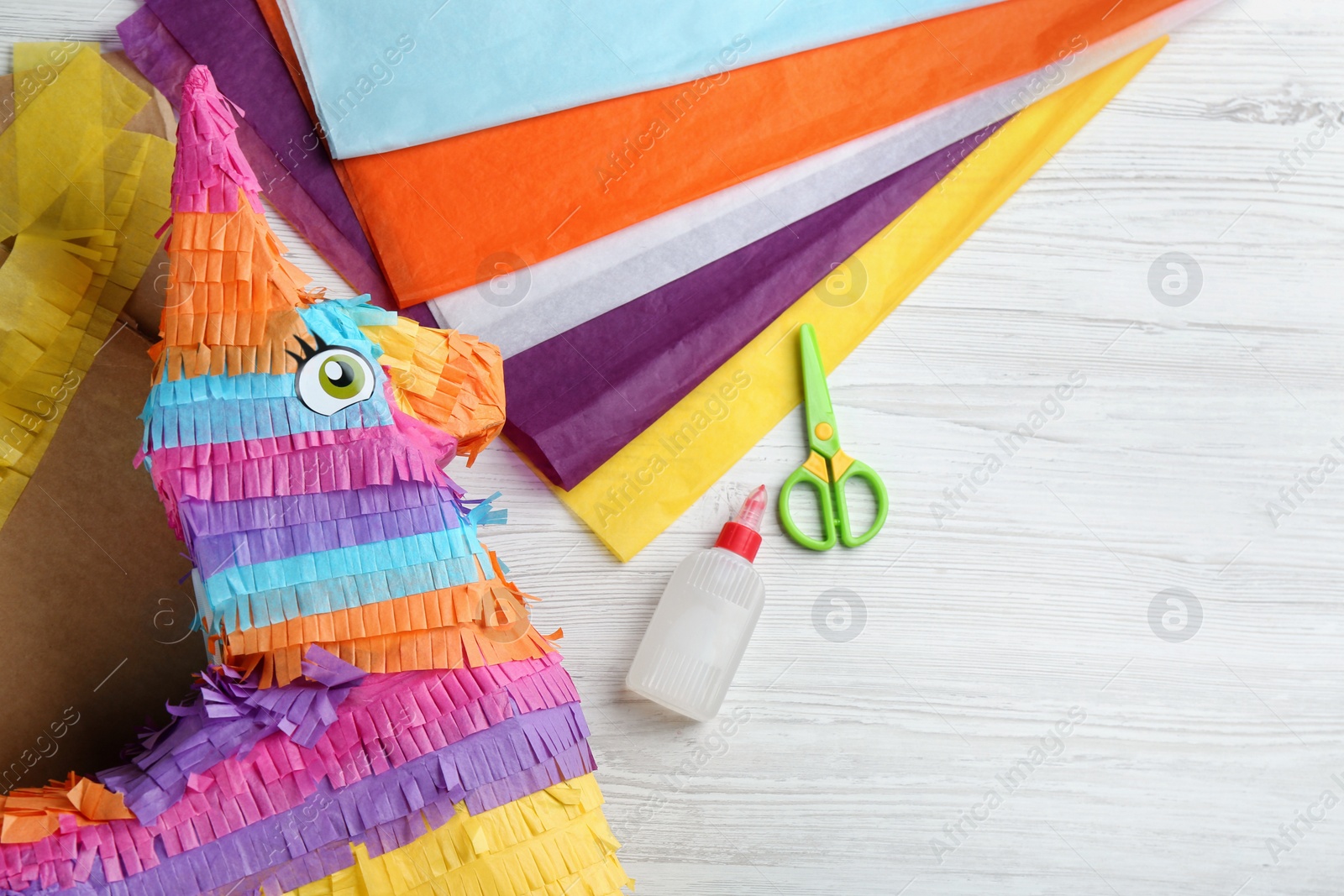 Photo of Flat lay composition with cardboard donkey and materials on white wooden table, space for text. Pinata DIY