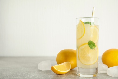 Photo of Cool freshly made lemonade, ice cubes and fruits on grey table. Space for text