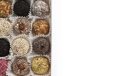 Photo of Different delicious vegan candy balls in box on white background, top view