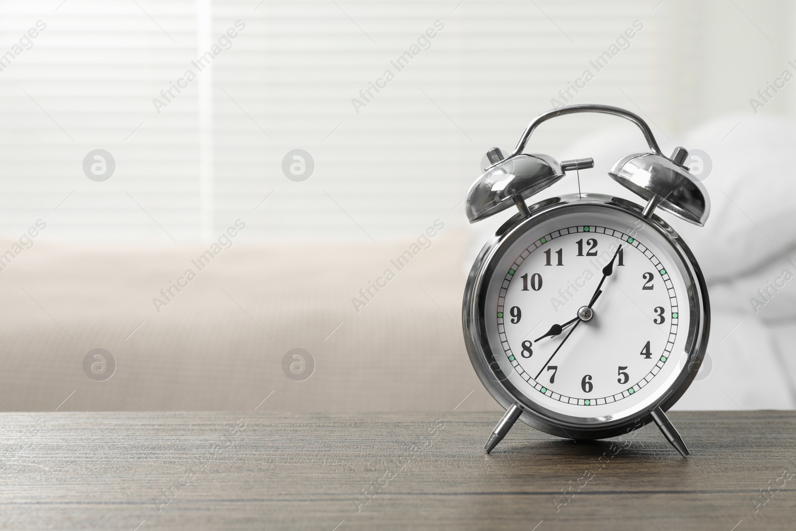 Photo of Silver alarm clock on wooden table in bedroom, space for text