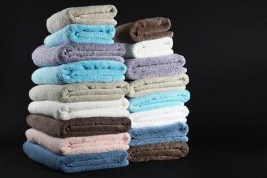 Photo of Different fresh soft terry towels on dark background