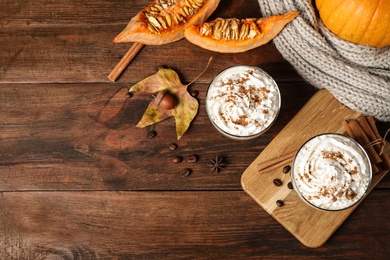 Glasses with tasty pumpkin spice latte on wooden table, flat lay. Space for text