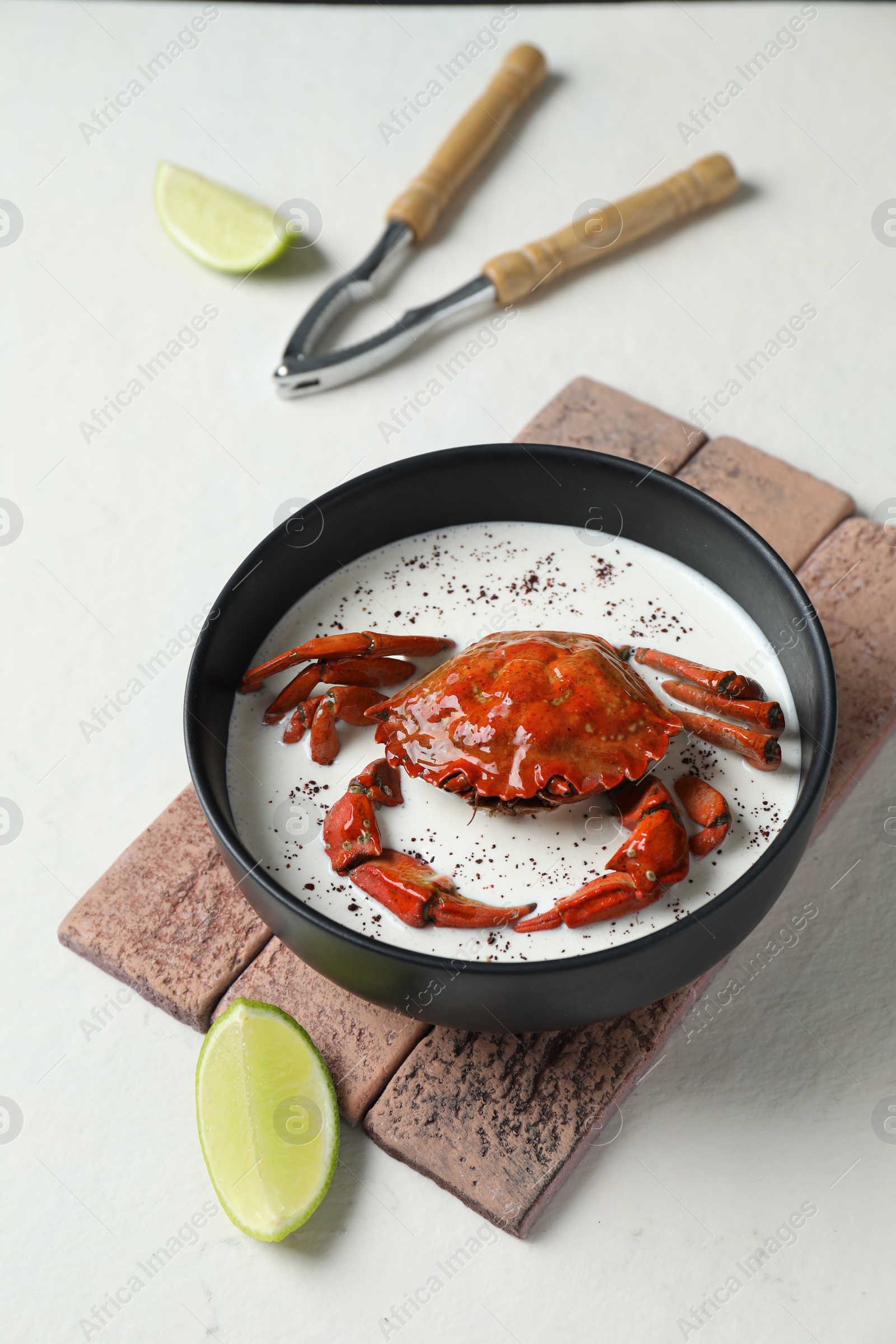 Photo of Delicious boiled crab with cream sauce and lime served on white table, above view
