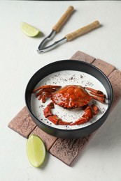 Delicious boiled crab with cream sauce and lime served on white table, above view