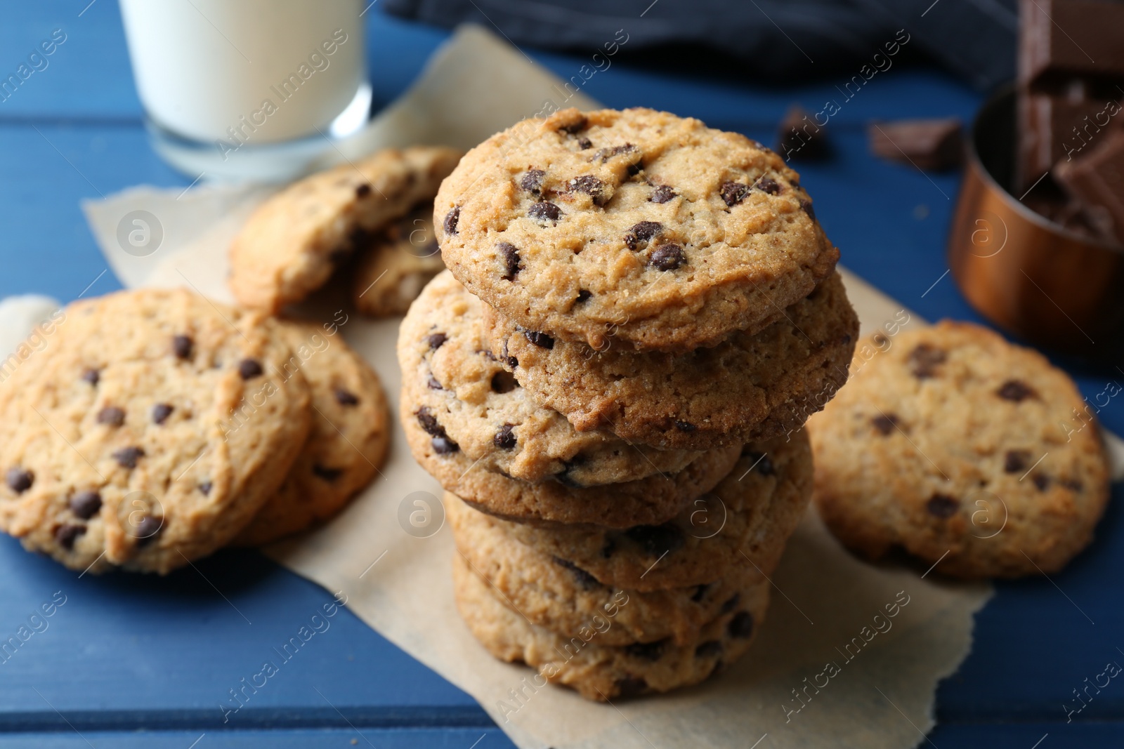 Photo of Tasty chocolate chip cookies and glass of milk on blue wooden table, closeup