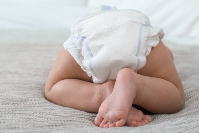 Cute little baby in diaper on bed