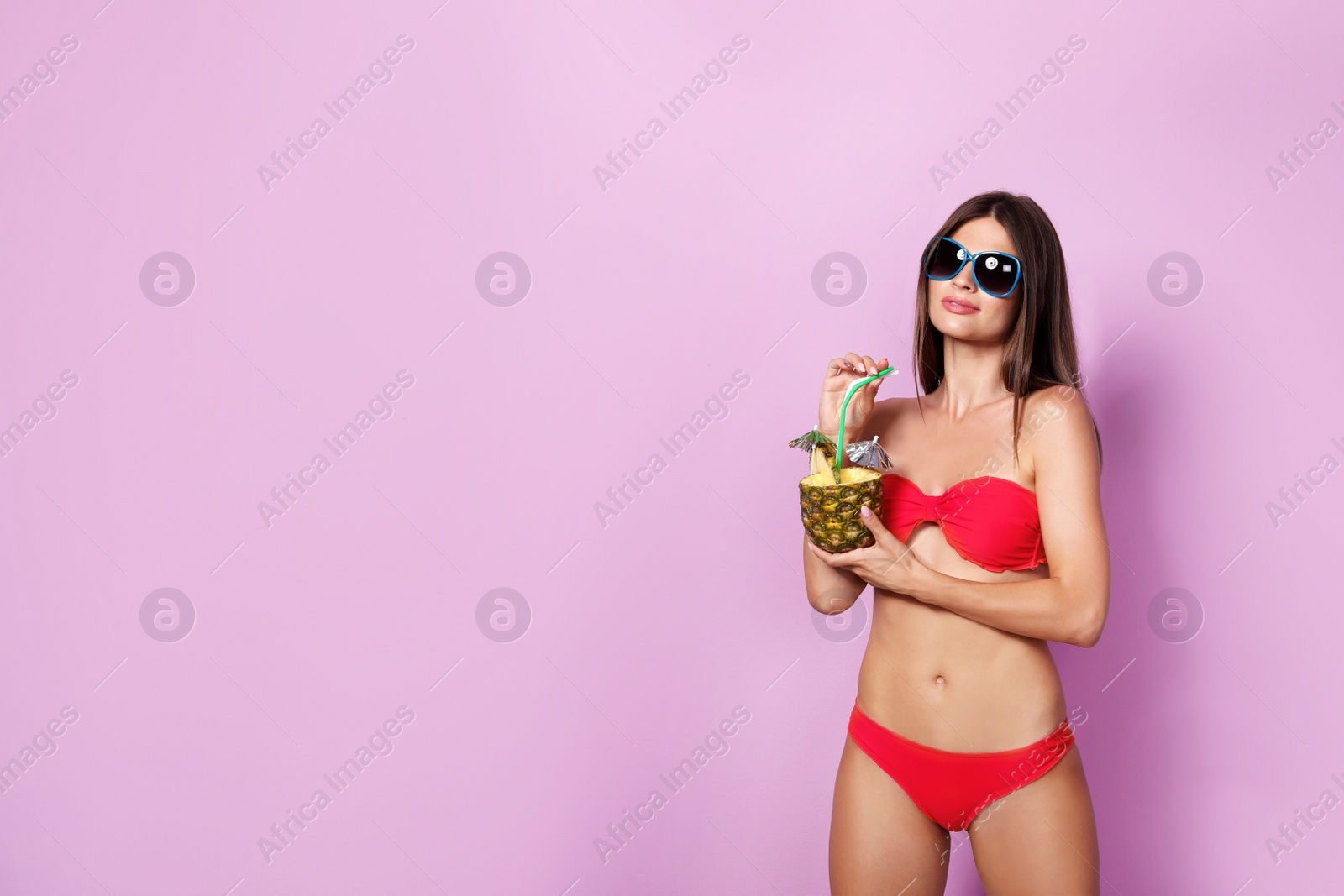 Photo of Sexy young woman in bikini with pineapple cocktail on color background