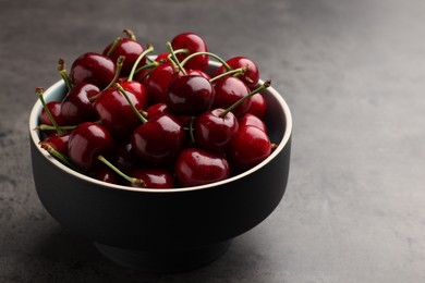 Photo of Bowl with ripe sweet cherries on dark grey table, closeup