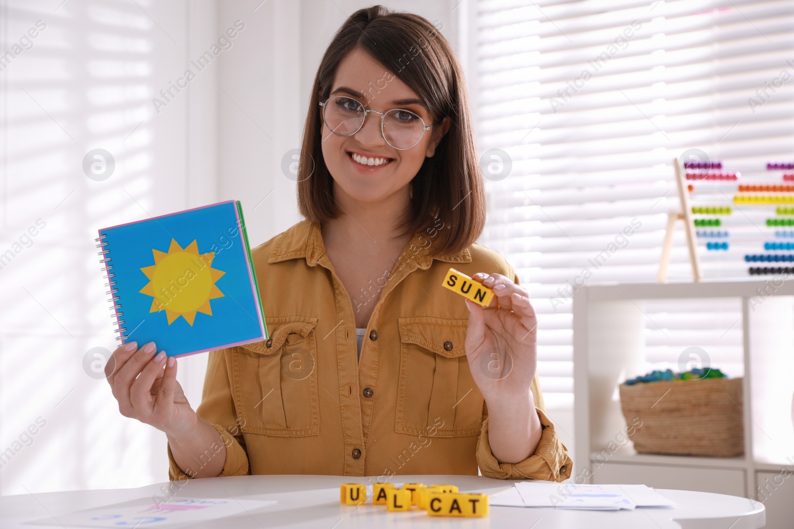 Photo of Happy female English teacher giving lesson indoors. Early childhood education