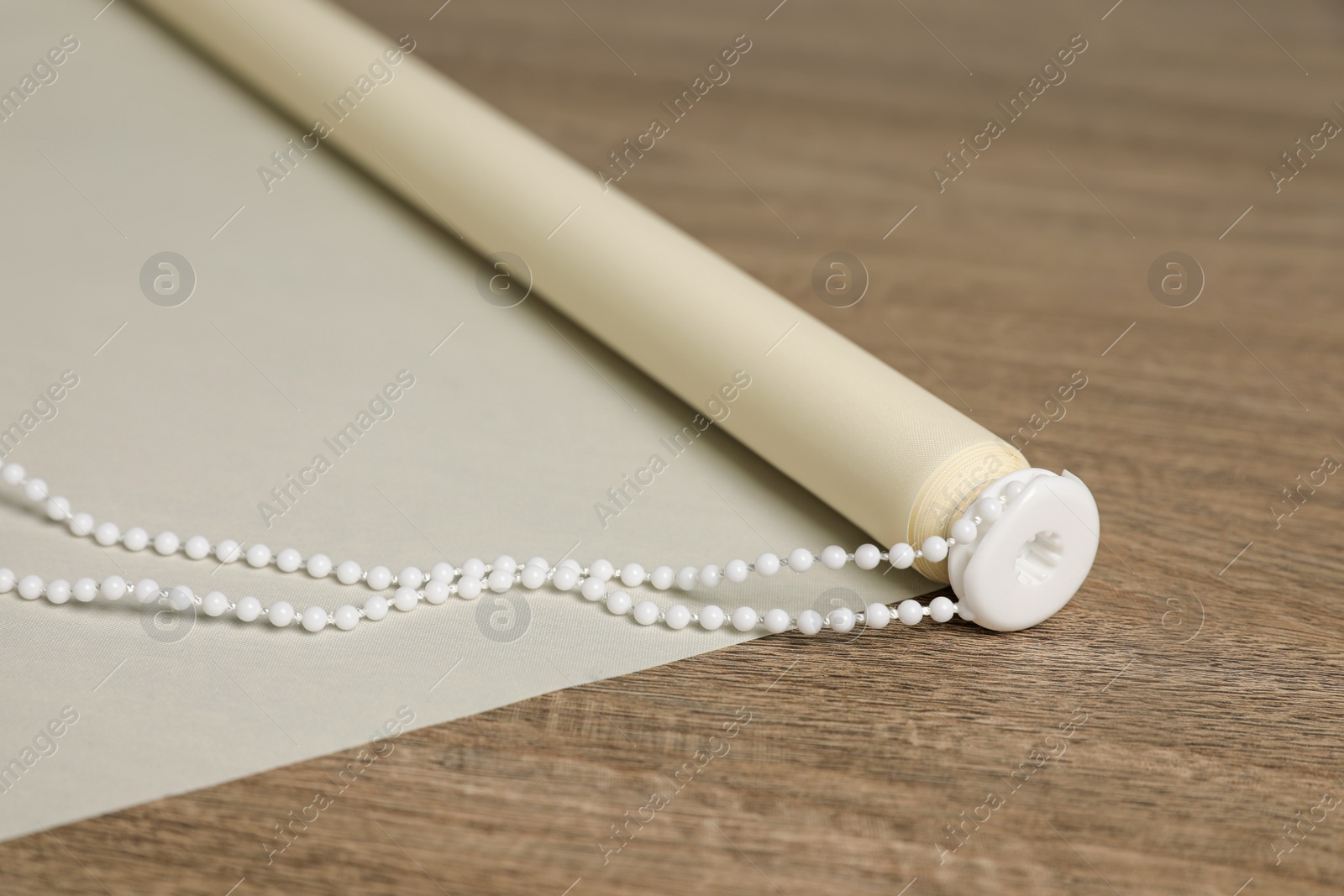 Photo of Stylish roller window blinds on wooden table, closeup