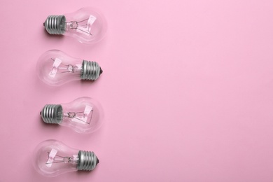 Photo of New incandescent lamp bulbs on pink background, top view. Space for text