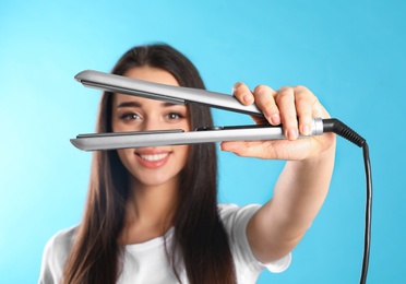 Photo of Happy woman with hair iron on color background