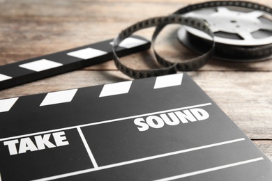 Clapperboard and reel on wooden table, closeup. Cinema production