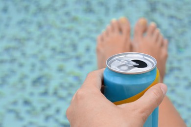 Photo of Woman holding aluminum can with beverage near swimming pool, closeup. Space for text