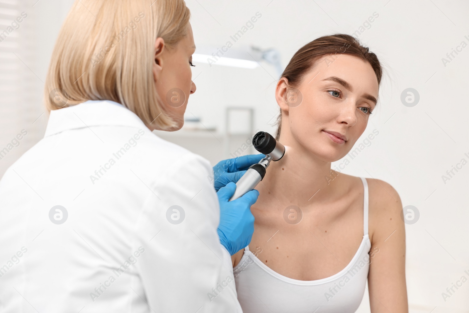 Photo of Dermatologist with dermatoscope examining patient in clinic