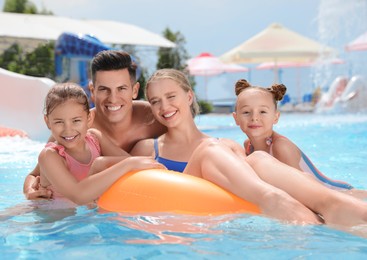 Photo of Happy family with inflatable ring in swimming pool at water park