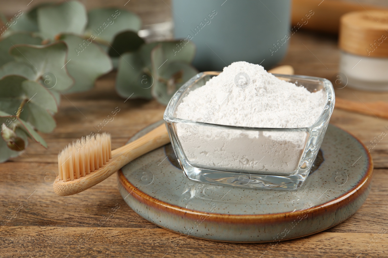 Photo of Tooth powder and brush on wooden table, closeup