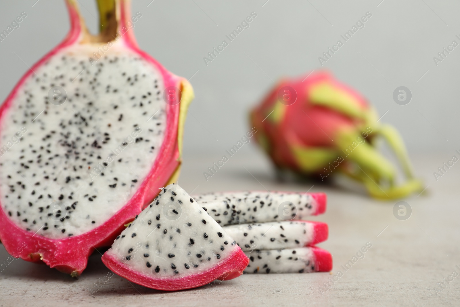 Photo of Delicious cut dragon fruit (pitahaya) on grey table, closeup