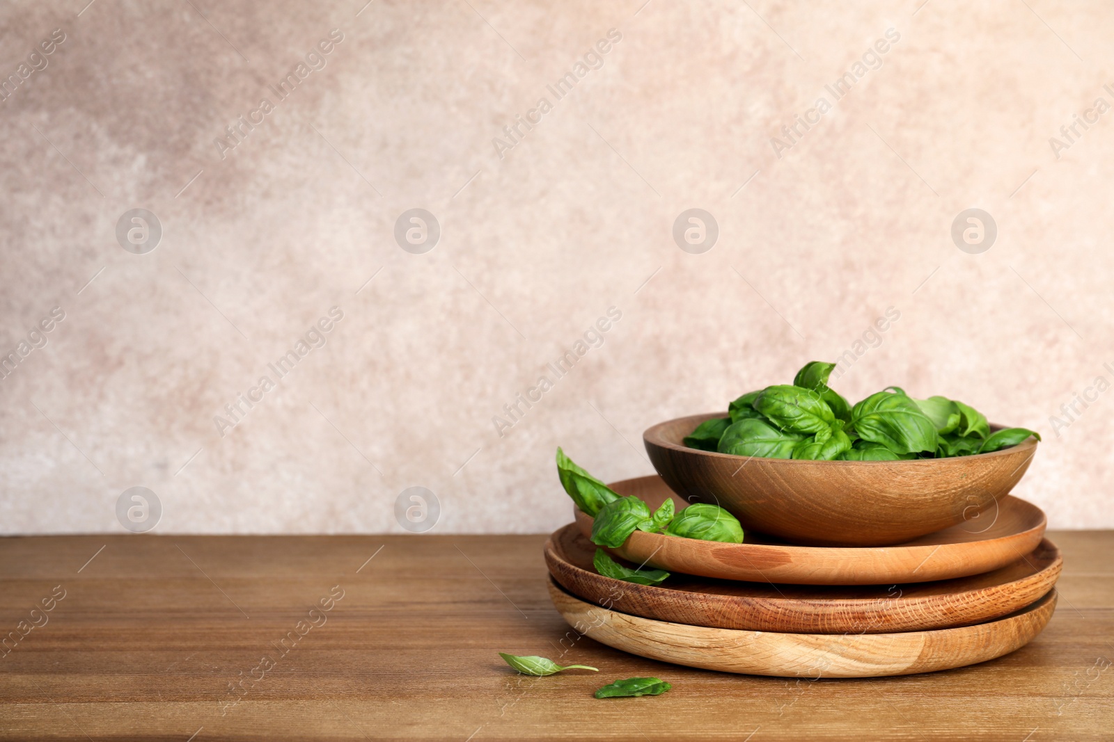 Photo of Dishware with fresh basil leaves on wooden table. Space for text