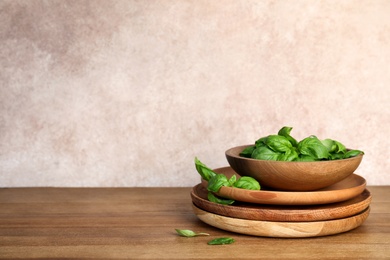 Photo of Dishware with fresh basil leaves on wooden table. Space for text