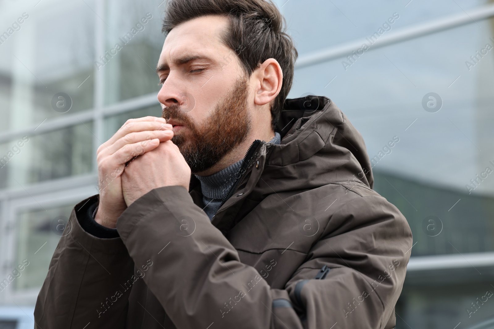 Photo of Sick man coughing on city street. Cold symptoms