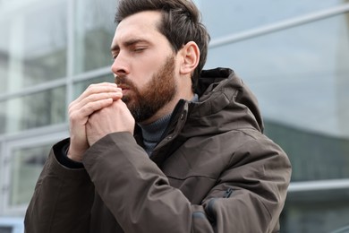 Sick man coughing on city street. Cold symptoms