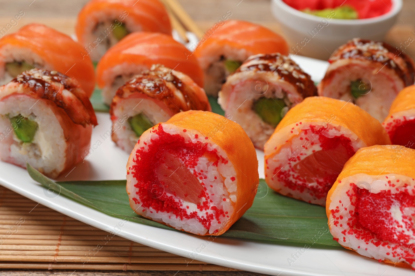 Photo of Different delicious sushi rolls on white plate, closeup