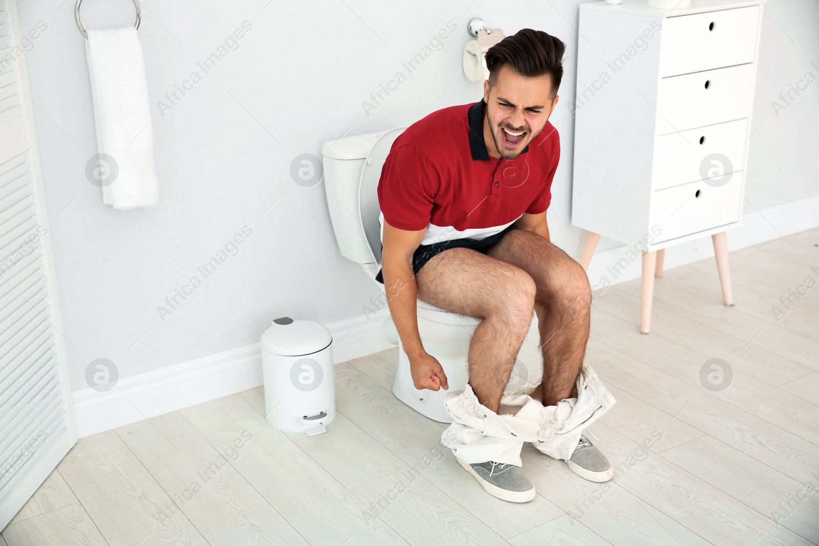 Photo of Young man suffering from diarrhea on toilet bowl at home
