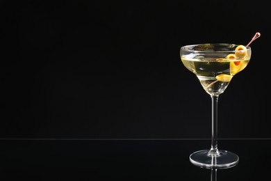 Martini cocktail with olives on dark background, space for text