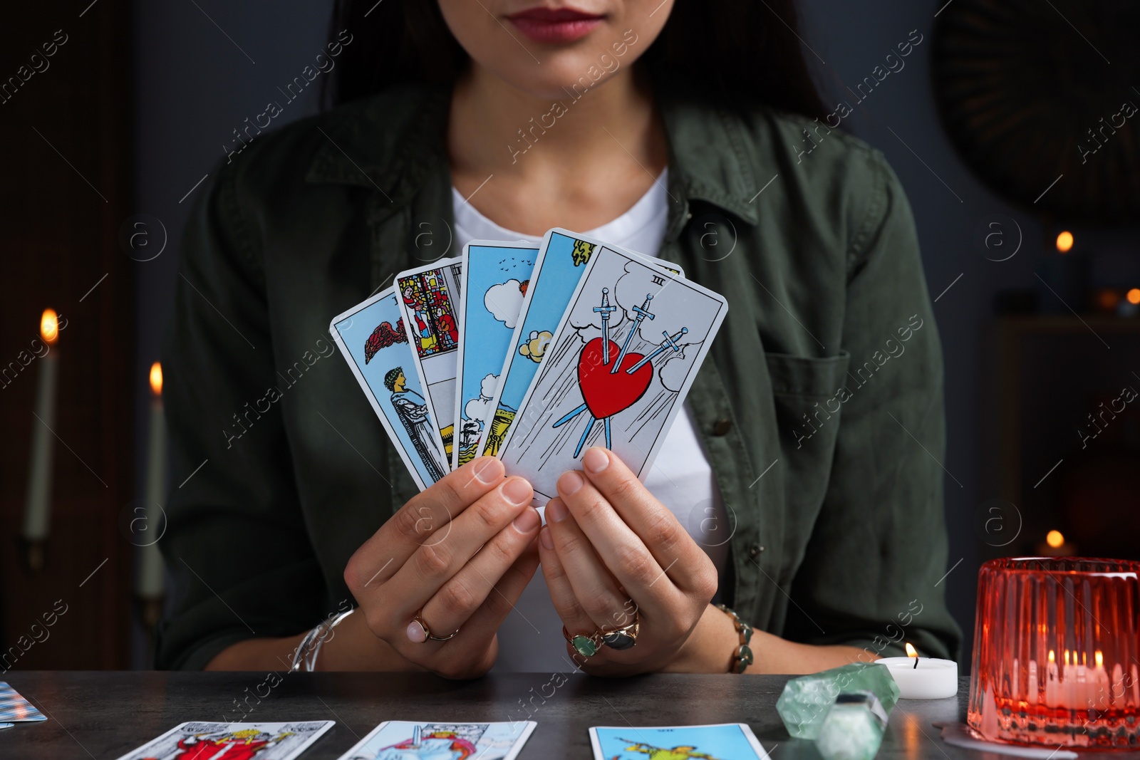 Photo of Fortune teller with tarot cards at grey table indoors, closeup