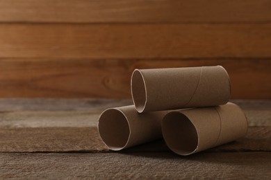 Empty toilet paper rolls on wooden table, space for text