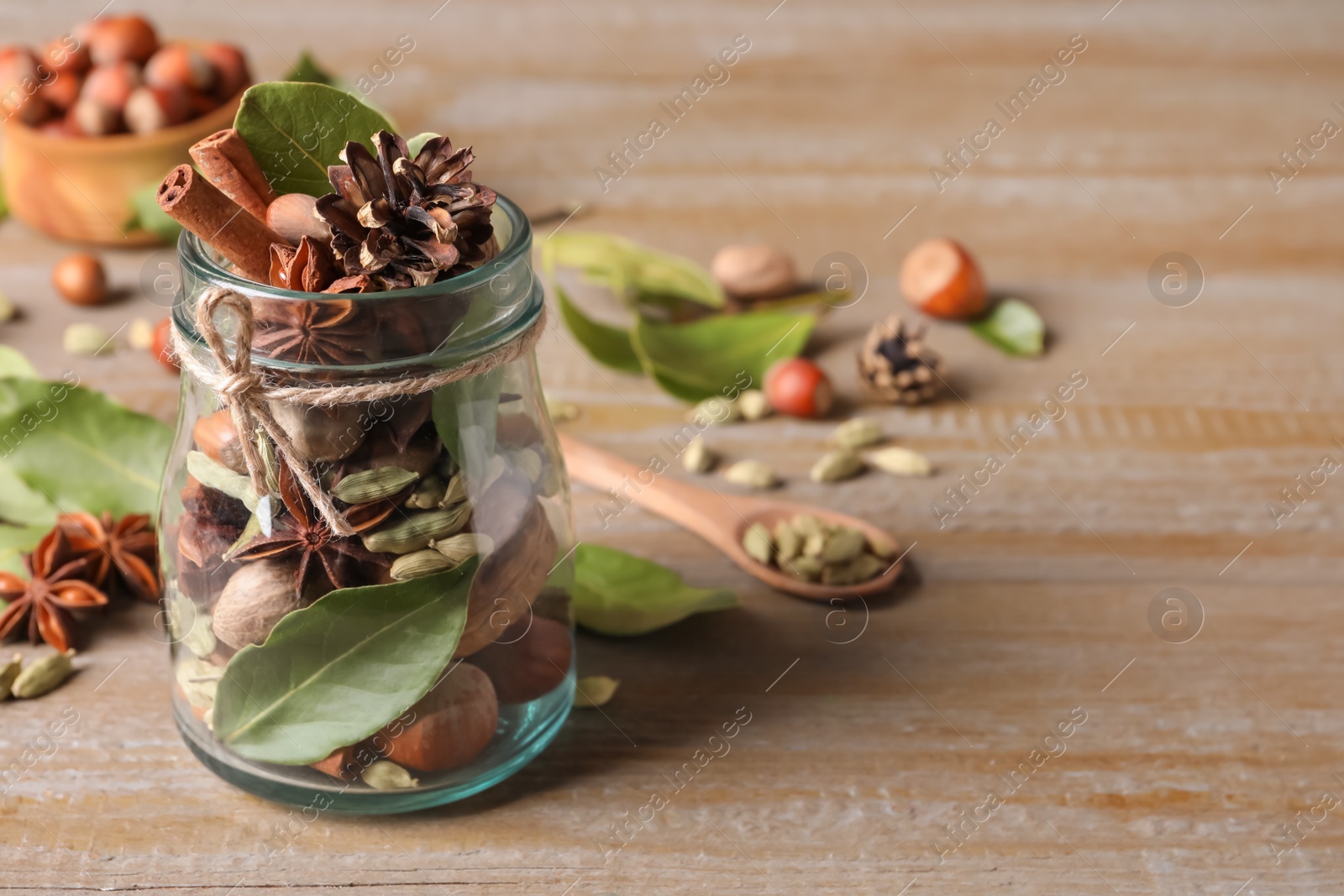 Photo of Aromatic potpourri in glass jar on wooden table. Space for text