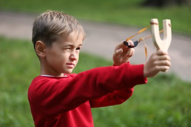 Little boy playing with slingshot in park