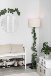 Hallway interior with stylish furniture and round mirror on light wall