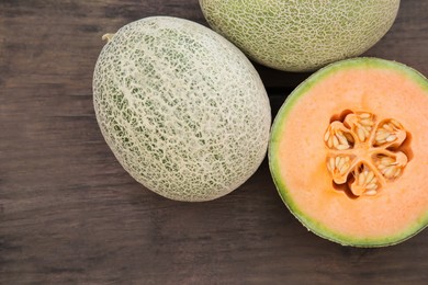 Whole and cut fresh ripe melons on wooden table, flat lay