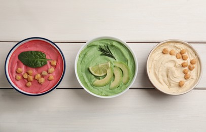 Different delicious hummuses on white wooden table, flat lay