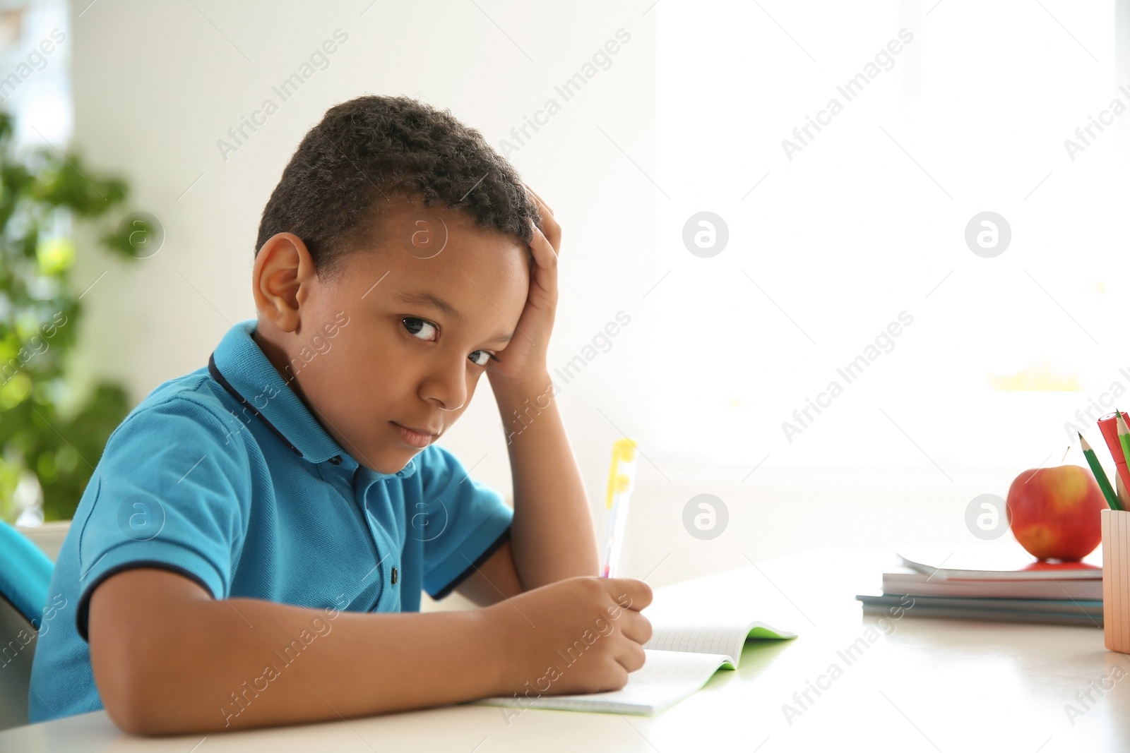 Photo of Cute little child doing assignment at desk in classroom. Elementary school