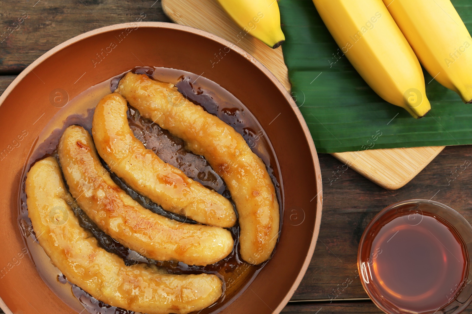 Photo of Delicious fresh and fried bananas with rum on wooden table, flat lay