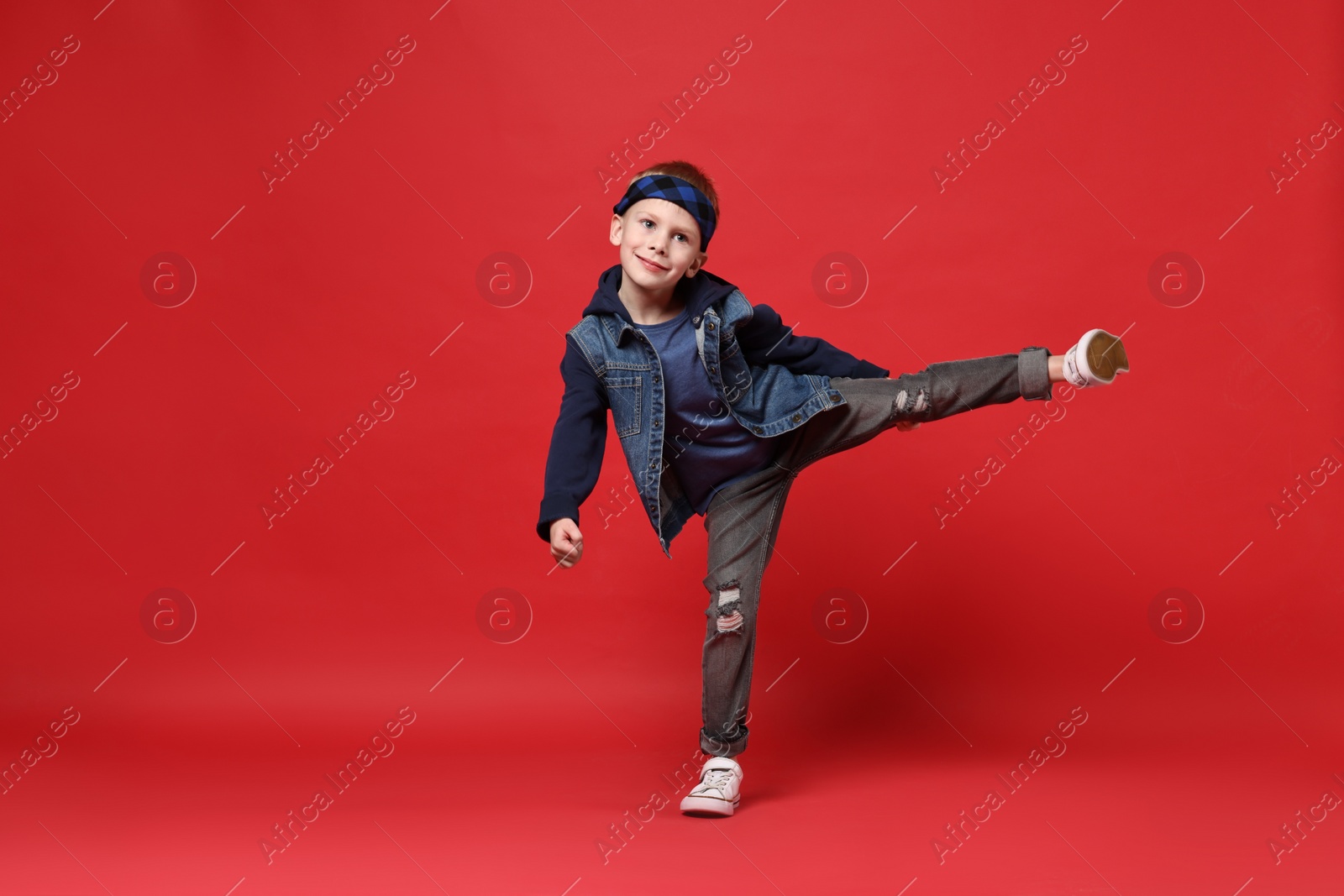 Photo of Happy little boy dancing on red background