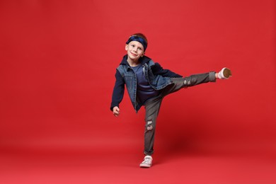 Photo of Happy little boy dancing on red background