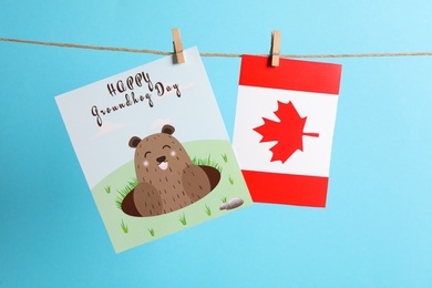 Happy Groundhog Day greeting card and Canada flag hanging on light blue background