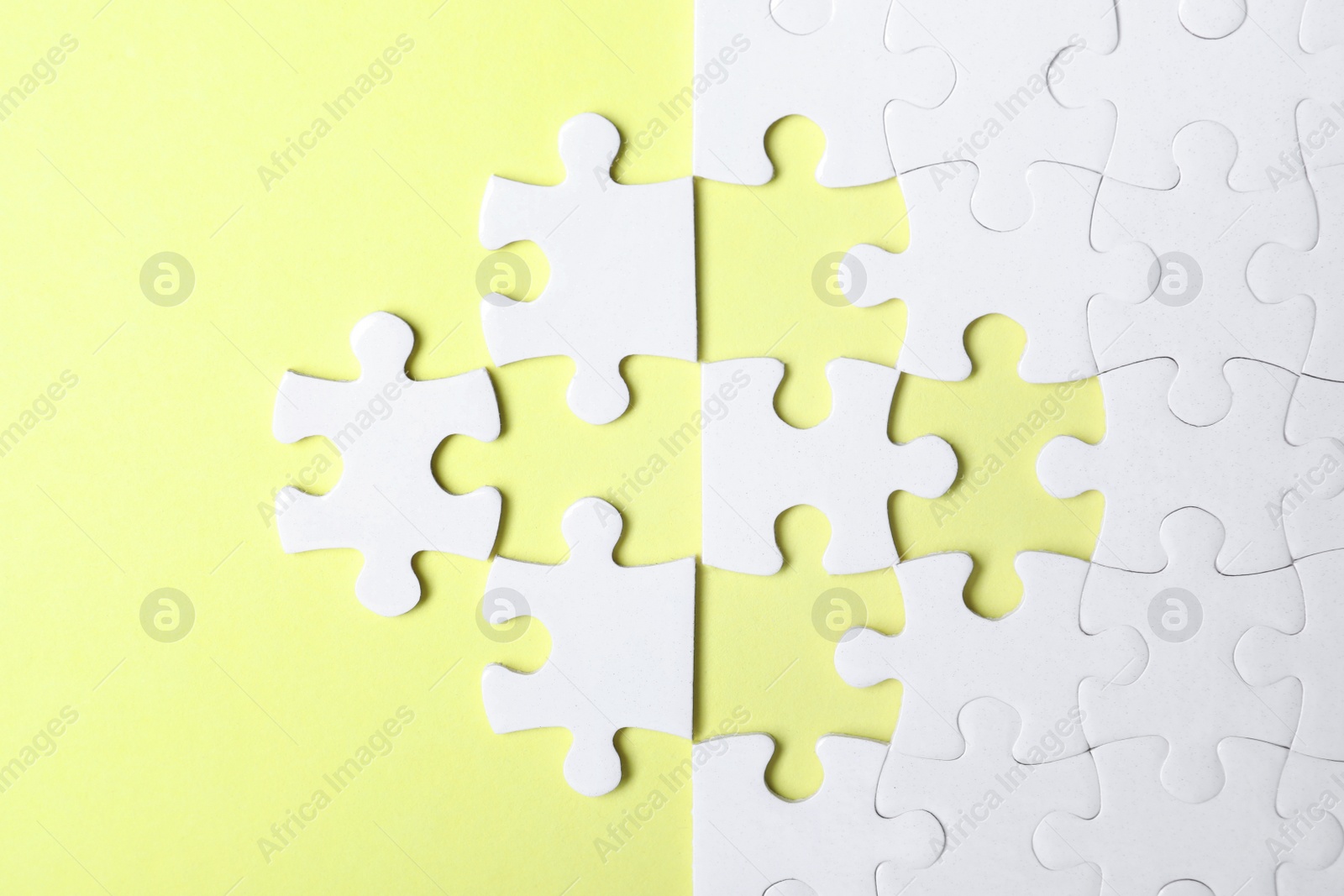 Photo of Blank white puzzle with separated pieces on yellow background, flat lay