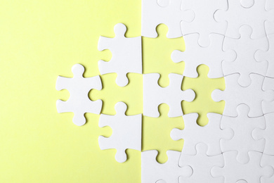 Photo of Blank white puzzle with separated pieces on yellow background, flat lay