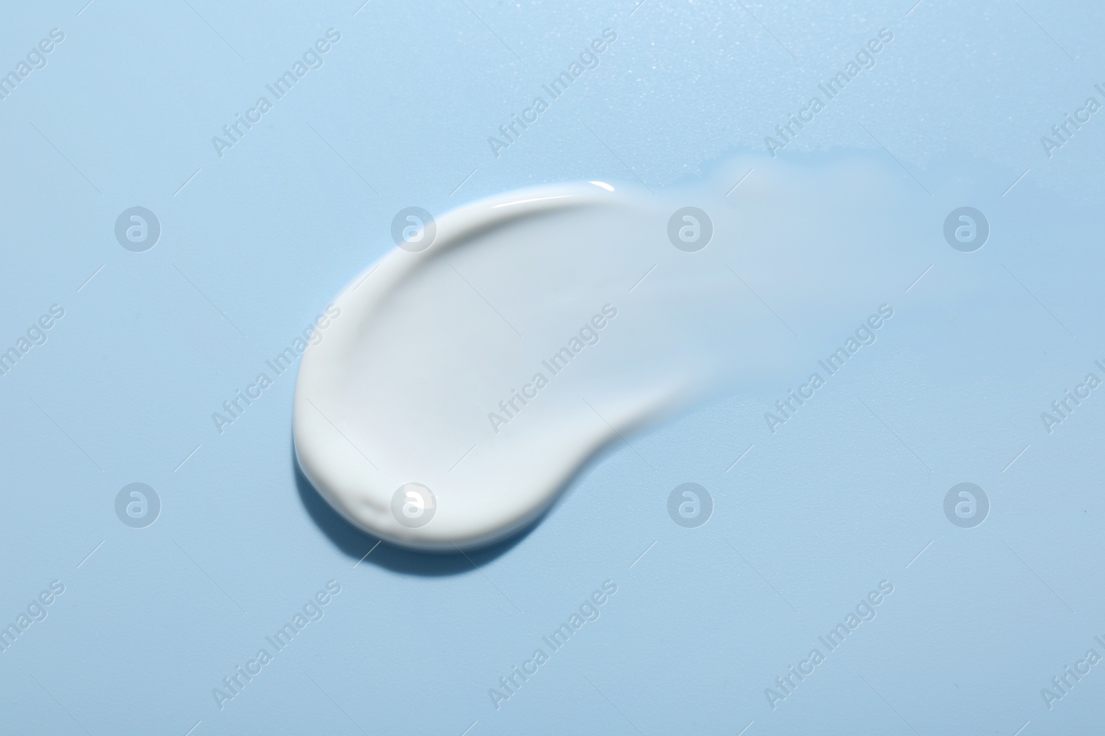 Photo of Sample of face cream on light blue background, top view