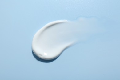 Photo of Sample of face cream on light blue background, top view