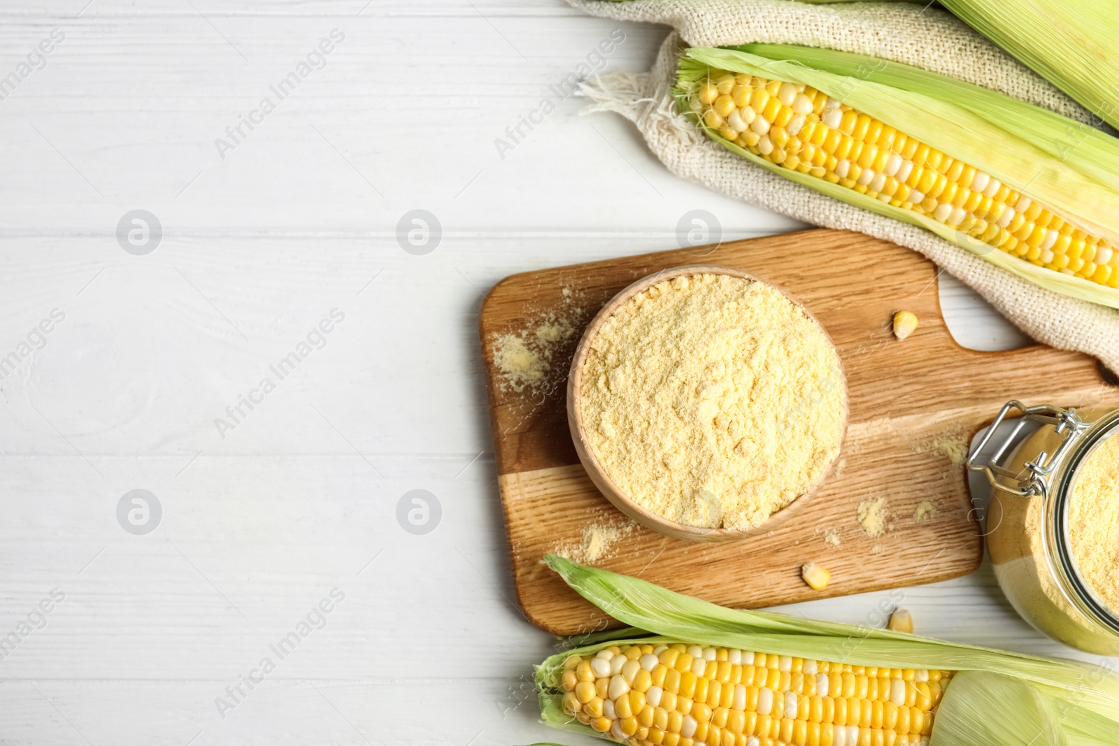 Photo of Corn flour in bowl on white wooden table, flat lay. Space for text